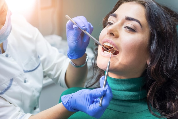 Manos del dentista en el trabajo Espejo bucal y sonda Guía de seguro dental