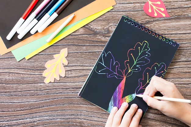 Foto manos dibujando hojas de colores en un cuaderno