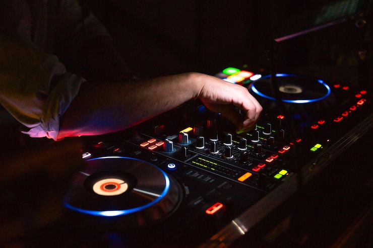Foto las manos del dj ajustan varios controles de pista en el mezclador de sonido de dj