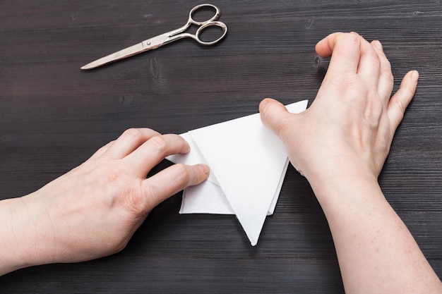 Las manos doblan una hoja de papel para hacer una figura