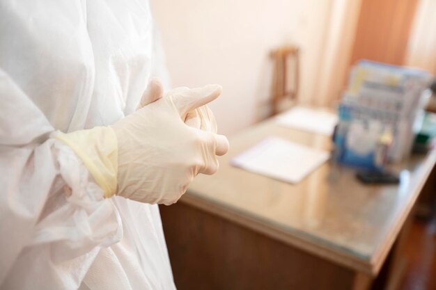 Manos del doctor con guantes de goma en el fondo de la oficina