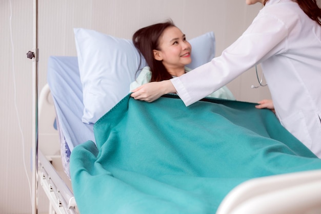 Manos doctora usando una manta para mujeres enfermas en la habitación del hospitalDoctor dando una consulta y aliento al paciente