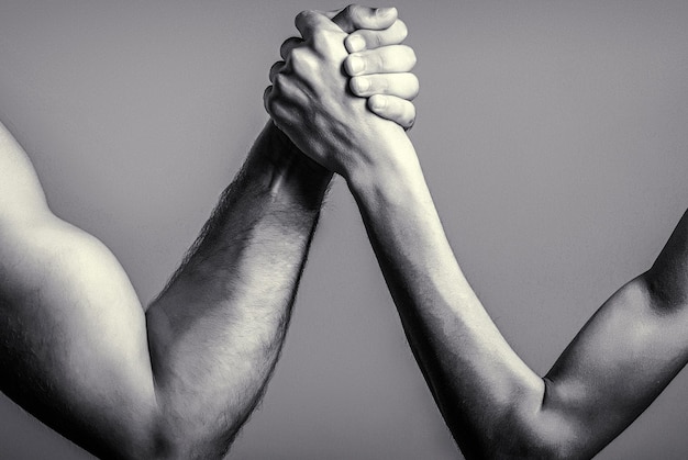 Foto manos de dos hombres entrelazadas lucha de brazo fuerte y débil partido desigual lucha de brazo mano delgada de lucha de brazo y un brazo grande y fuerte en el estudio blanco y negro