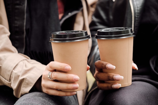 Manos de dos mujeres interculturales con bebidas