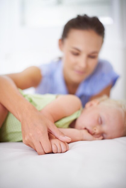 Foto las manos durmiendo y la madre con el bebé en la cama para la unión relajarse y dulce relación linda sonrisa feliz y madre joven viendo niña niño o niño pequeño tomando una siesta en el dormitorio o la guardería en casa