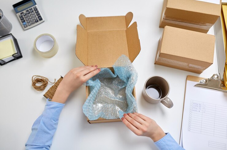 Foto manos empacando taza a la caja de paquetes en la oficina de correos