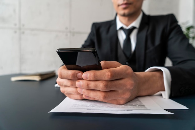 Foto manos de empresario con teléfono y documentos.