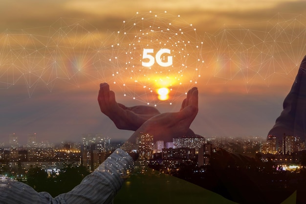 Manos de empresarios muestran 5G sobre un fondo de puesta de sol urbana