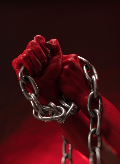 Las manos ensangrentadas apretadas en puños con los grilletes de una cadena de metal simbolizan la protesta contra la esclavitud y la lucha por la libertad.