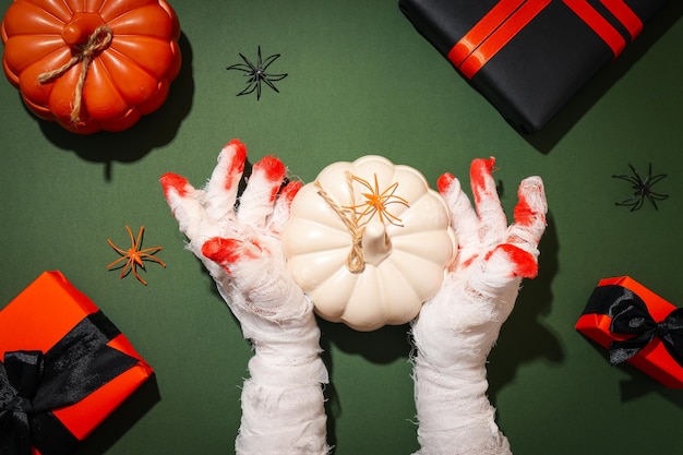 Foto manos envueltas en una venda con una calabaza y regalos.