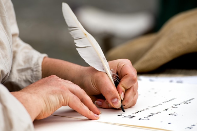 Manos escribiendo una carta con un penacho