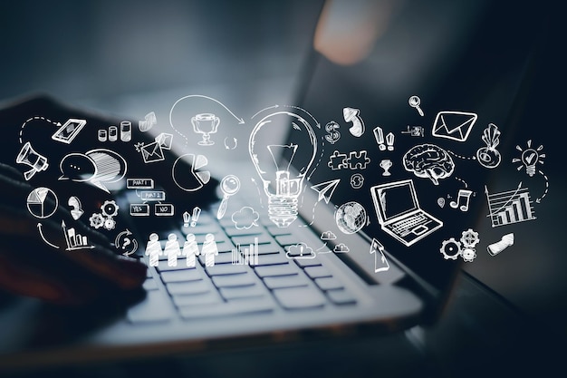 Manos escribiendo en una computadora portátil con gráficos creativos que representan ideas y tecnología flotando sobre el teclado en un fondo borroso