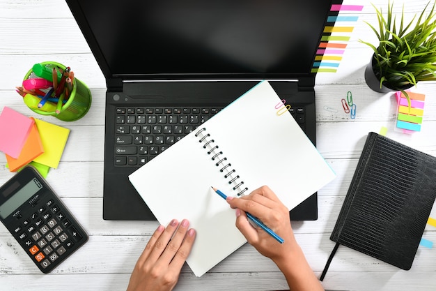 Manos escribiendo en un cuaderno con lápiz e