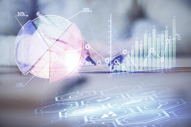 Manos escribiendo información sobre el mercado de valores en el bloc de notas gráficos de divisas hologramas en el frente concepto de investigación exposición múltiple