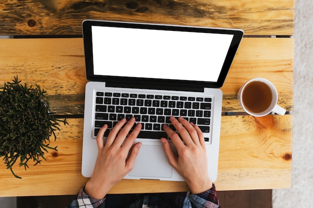 Manos escribiendo en el teclado del ordenador portátil colocado en el escritorio de oficina