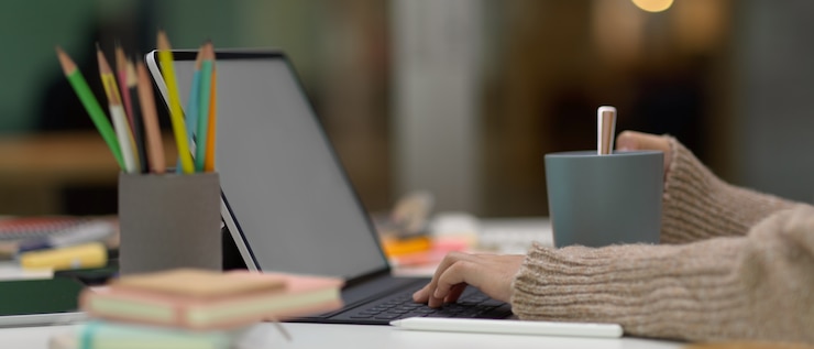 Foto manos escribiendo en el teclado del portátil en la mesa de trabajo