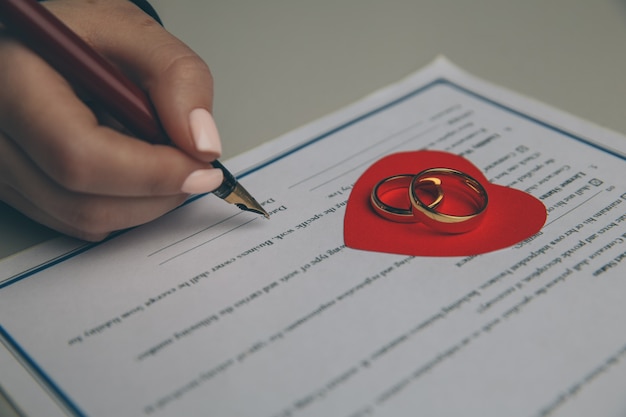 Manos de esposa, esposo firmando decreto de divorcio, disolución, cancelación de matrimonio, documentos legales de separación