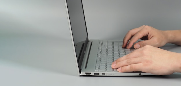 Manos está escribiendo en la computadora portátil o portátil sobre fondo gris. Estudio de disparo. Vista superior del ojo.