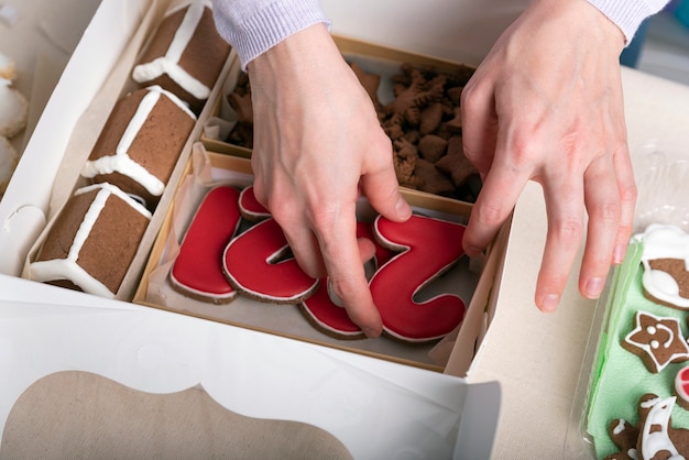 Las manos están empacando galletas de jengibre en una caja de regalo. De cerca.