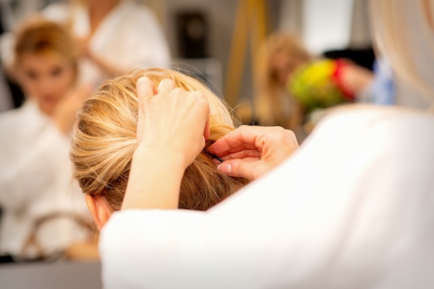 Manos del estilista haciendo peluquería profesional de cabello largo femenino en un salón de belleza.