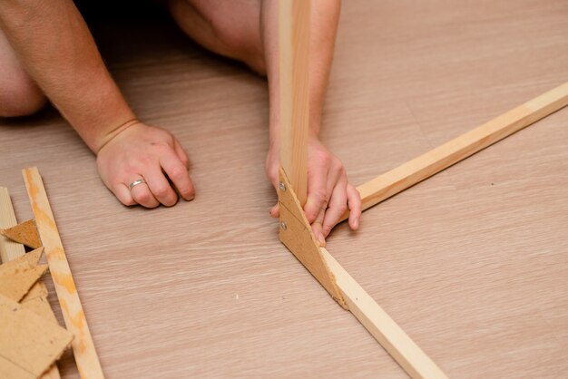 Manos europeas blancas del hombre con el destornillador que trabaja con madera y tornillos.