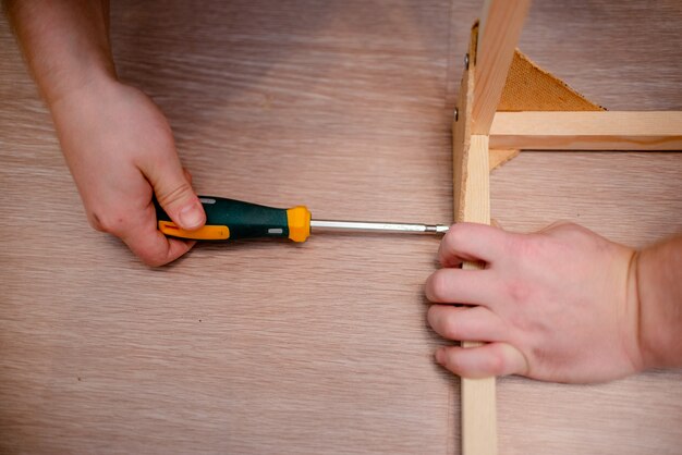 Manos europeas blancas del hombre con el destornillador que trabaja con madera y tornillos.