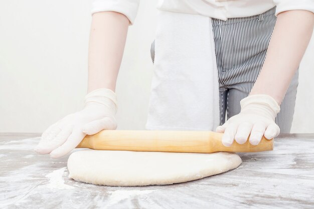 Las manos extienden la masa con un rodillo sobre un blanco