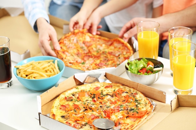 Manos de familia feliz comiendo pizza.