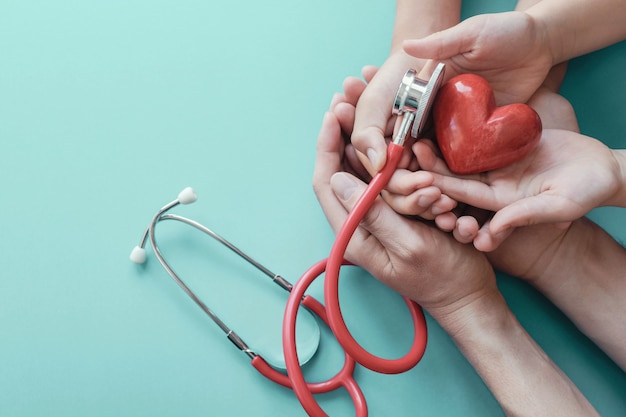 Manos familiares con corazón rojo con estetoscopio