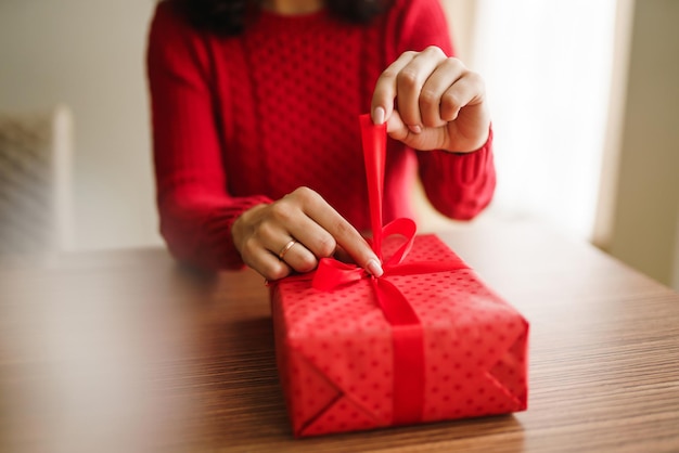 Manos femeninas abriendo caja de regalo roja Desempacando un regalo Concepto de celebración del día de San Valentín