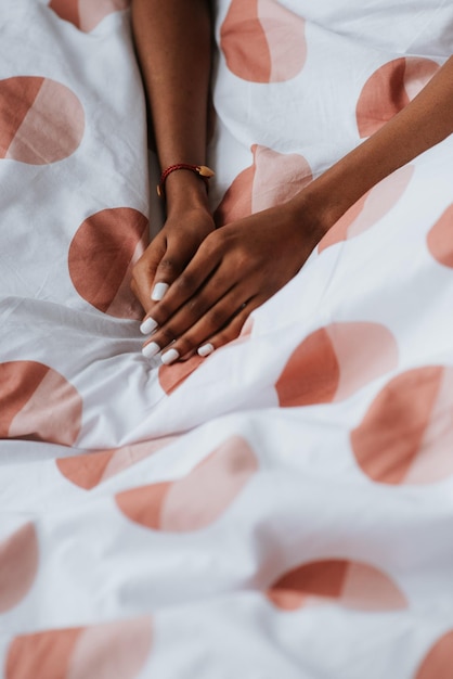 Manos femeninas africanas con manicura blanca en una cama