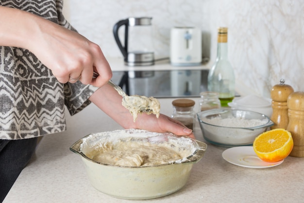 Las manos femeninas amasan en la moderna cocina minimalista, vista cercana