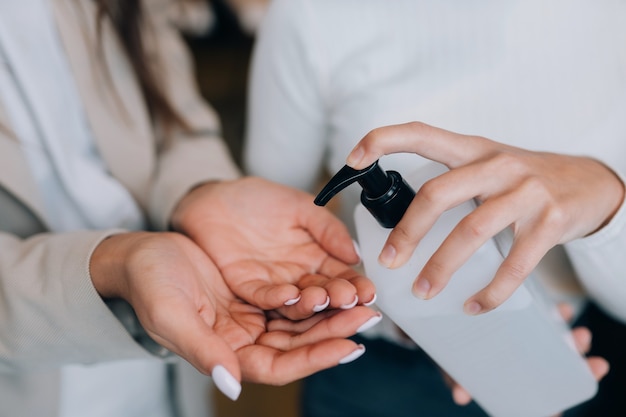 Manos femeninas aplicando jabón líquido antibacteriano