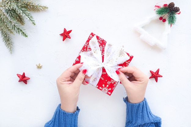 Manos femeninas atan un lazo en un regalo de Navidad