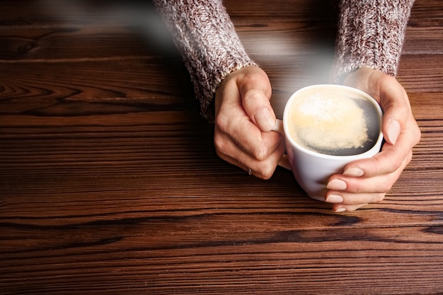 Manos femeninas y café sobre fondo de madera