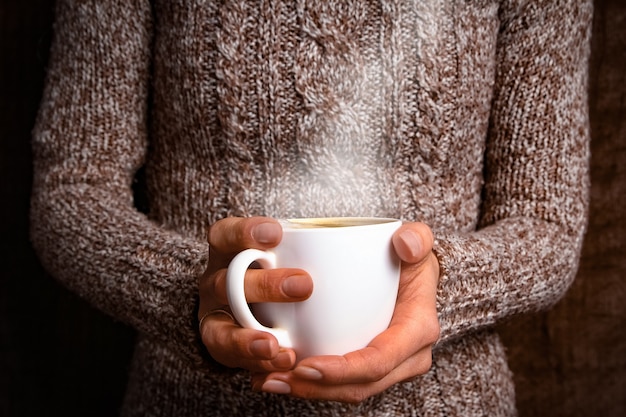 Manos femeninas y café sobre fondo de madera