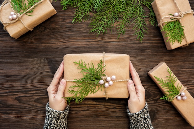 Manos femeninas con caja de regalo de Navidad en madera oscura