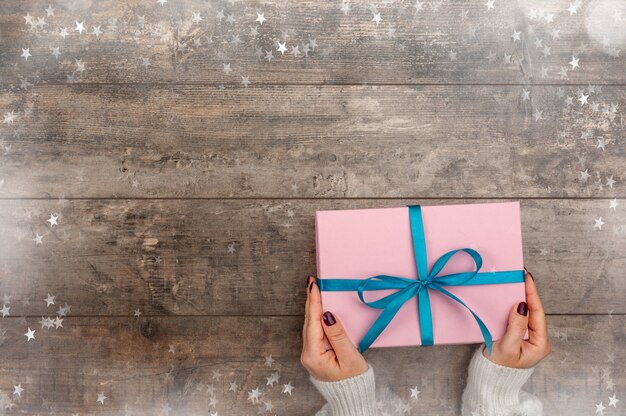 Manos femeninas con caja de regalo de Navidad sobre fondo de madera rústica Navidad y feliz año nuevo tema