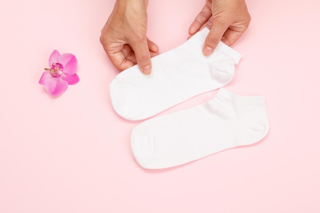 Manos femeninas con calcetines blancos de mujer sobre un fondo rosa Vista superior