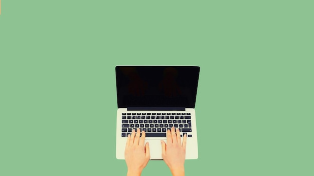 Manos femeninas de cerca mujer trabajando con una computadora portátil pantalla negra en blanco sobre fondo verde