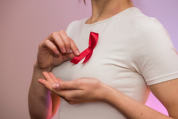 Manos femeninas con cinta roja. Publicidad social. Concepto de salud