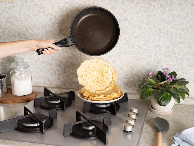 Manos femeninas cocinando panqueques finos