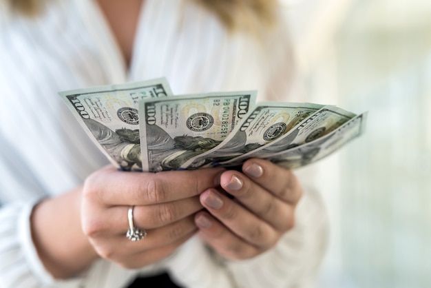 Manos femeninas contando billetes de un dólar estadounidense o pagando en efectivo de pie en el moderno centro comercial o centro comercial