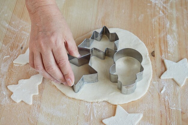 Foto manos femeninas cortan las galletas en forma de abeto. preparando galletas para hornear