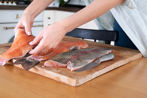 Manos femeninas cortando filete de pescado rojo Caviar rojo Eliminación de espinas de pescado Matanza de pescado rojo concepto meatxAxAFood