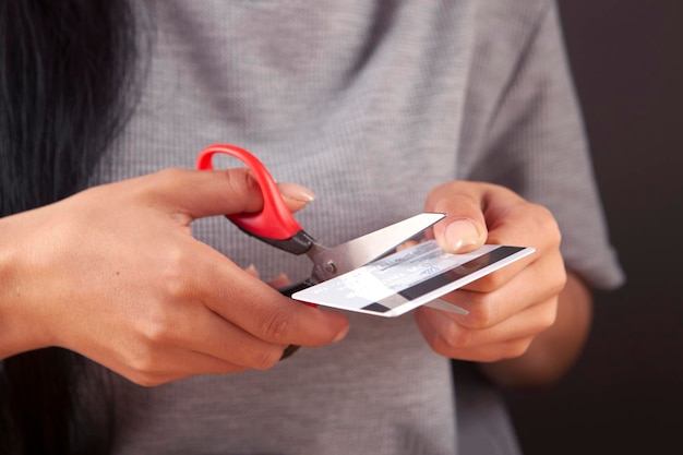 Manos femeninas cortando tarjeta de crédito con tijeras