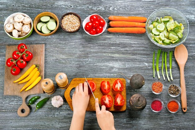 Foto manos femeninas cortando tomates en la vista superior de la mesa