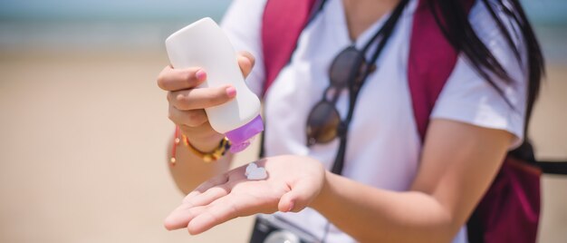 Manos femeninas con crema de protección solar en la playa.