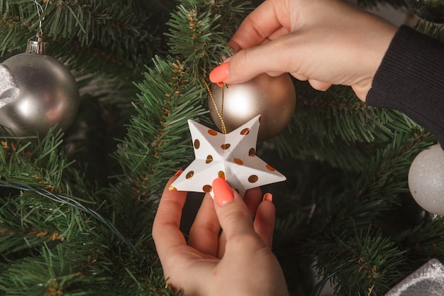 Manos femeninas decorar el árbol de navidad con juguetes