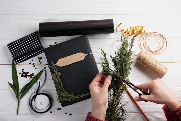 Manos femeninas decorar regalos sobre superficie de madera